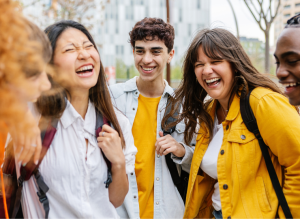 A group of young adults outdoors laughing together, wearing casual jackets and using British slang words and phrases