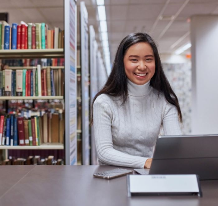 Bookshelves are visible in the background and she is reading about Your and You’re: What’s the Difference and When to Use Them