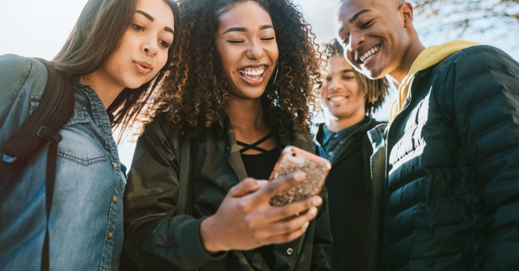 College students looking at a smartphone together indoors.