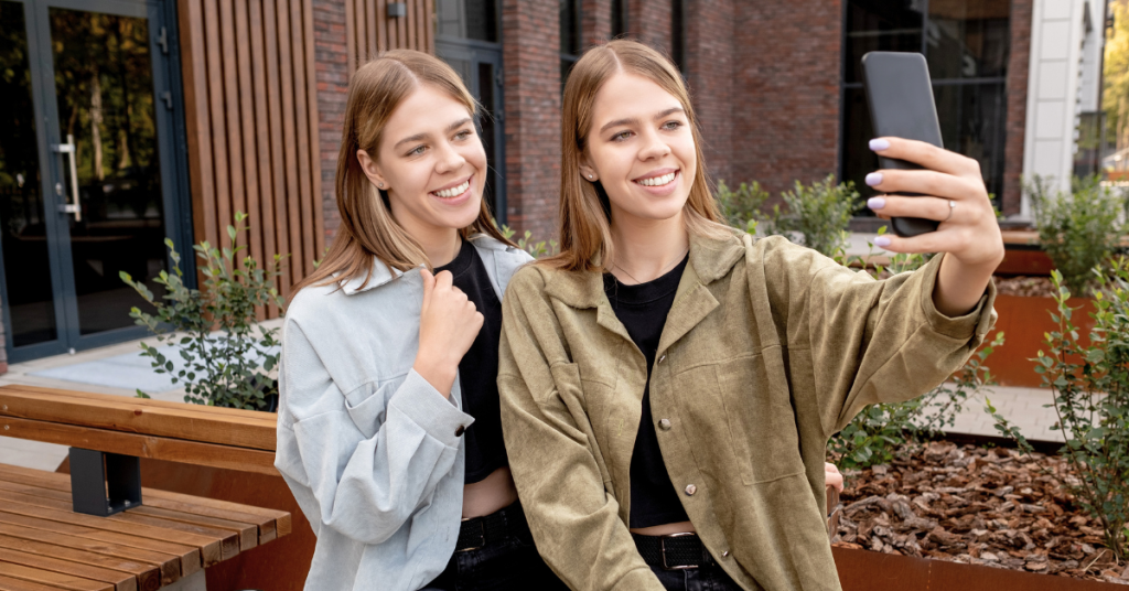 Friends smiling while looking at a smartphone producing content for TikTok