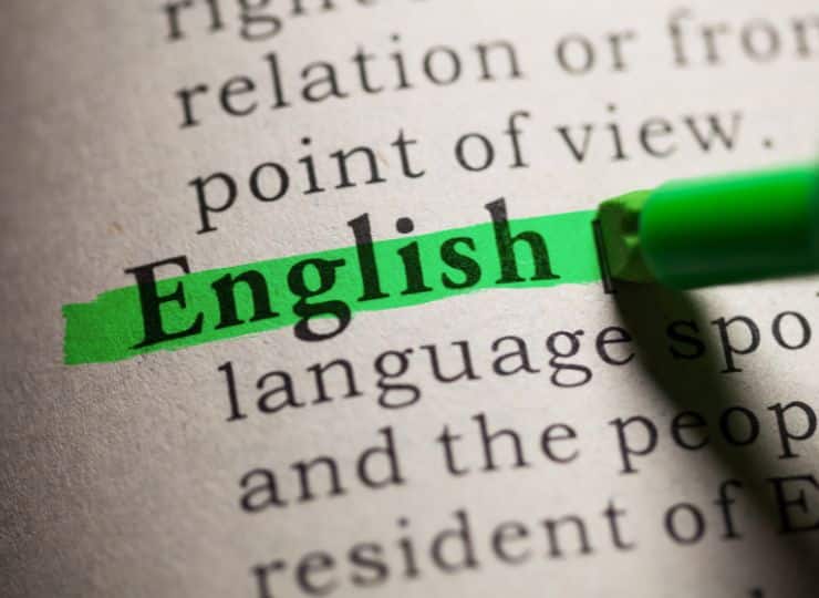 Close-up of a dictionary page with the word "English" highlighted in green. A green highlighter pen is visible over the word.